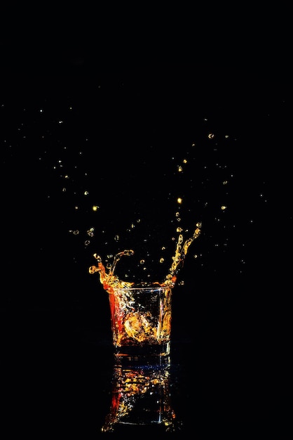 Whiskey with splash on black background brandy in a glass