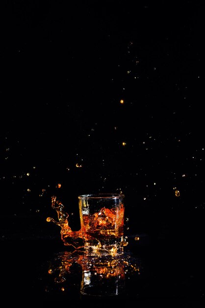 Whiskey with splash on black background brandy in a glass