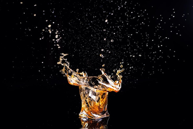 Whiskey with splash on black background brandy in a glass