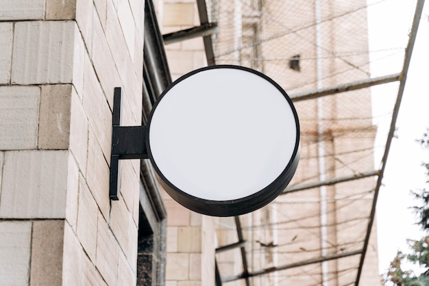 White advertising board on the building. Mock-up of a round street signboard for outdoor advertising on the background of the house