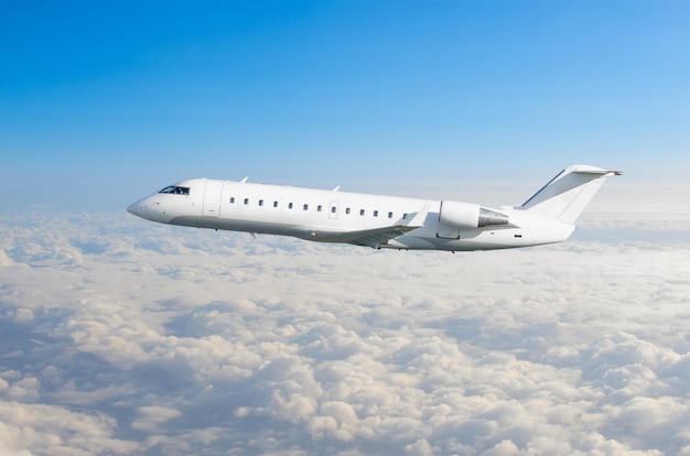 White airplane flies above the clouds.