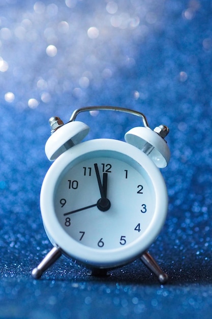 White alarm clock on a blue shiny background.