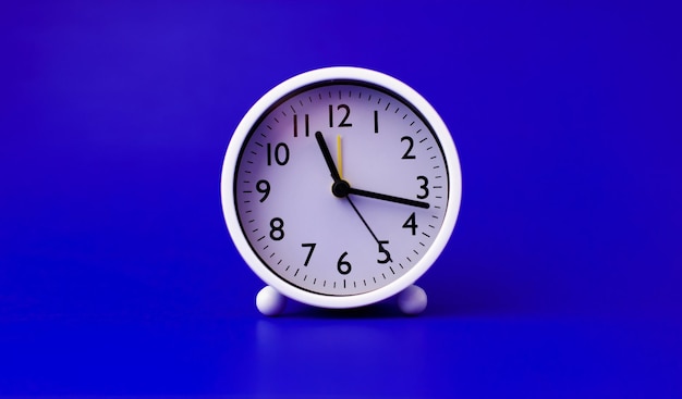 White alarm clock set on a blue background time concept and waking up