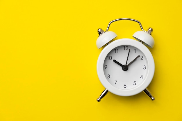 White analog alarm clock isolated on yellow background Concept of time management