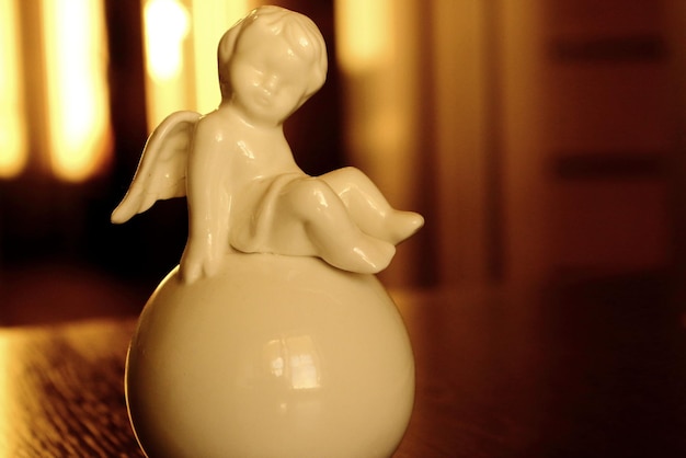 White angel on the ball statue Cute angel sculpture in warm light Decorative art