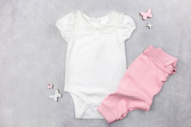 White baby girl bodysuit mockup flat lay with pink panties on the gray concrete surface