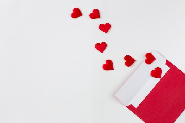 On a white background an envelope and red satin hearts are flying from it