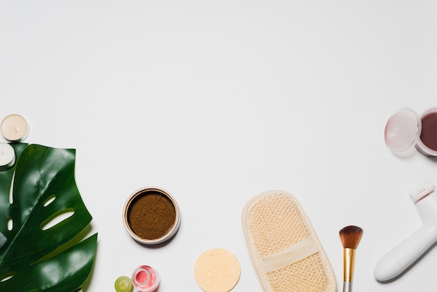 On white background lies a sponge, a scrub and a large leaf