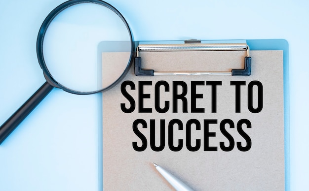 On a white background magnifier, a pen and a sheet of paper with the text Secret to Success . Business