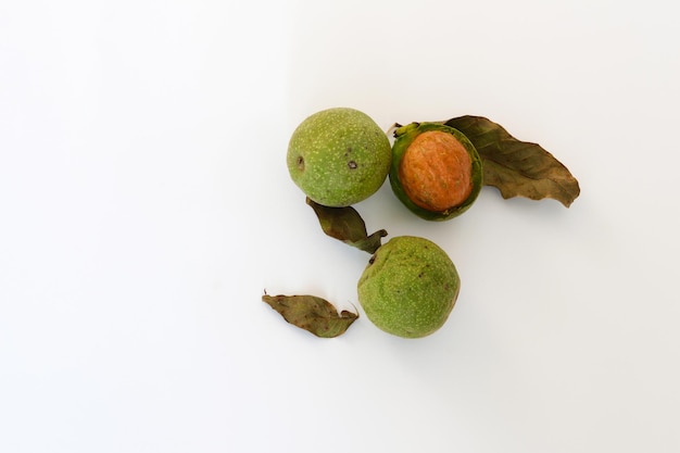 Photo a white background with green leaves and two green walnuts