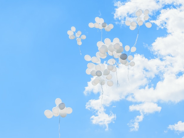 Photo white balloons fly high into the sky with clouds