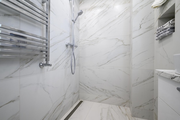 White bathroom interior with marble tiles on the walls