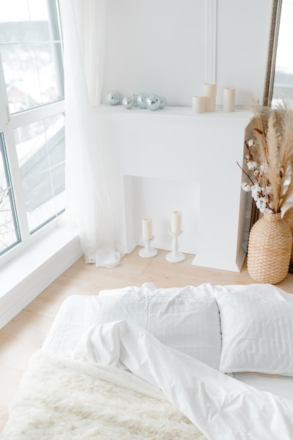 A white bed and a white decorative fireplace Cozy bright bedroom in minimalism style Minimalistic