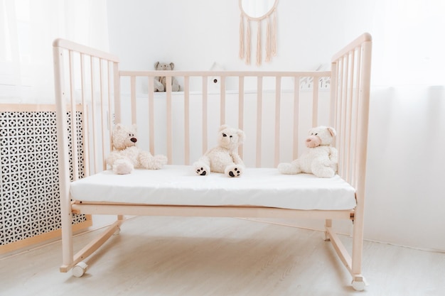 A white bedroom with a baby cot and teddy bears bright bedroom for a child