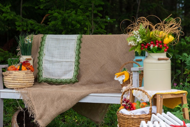 A white bench with wicker baskets of artificial flowers and fruits in the garden Yard decoration