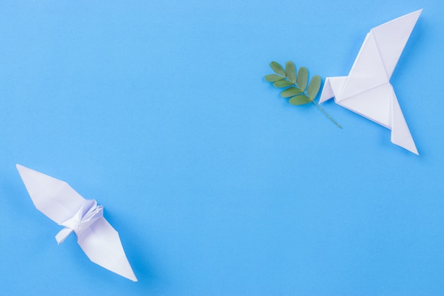 White bird made from paper carrying leaf branch