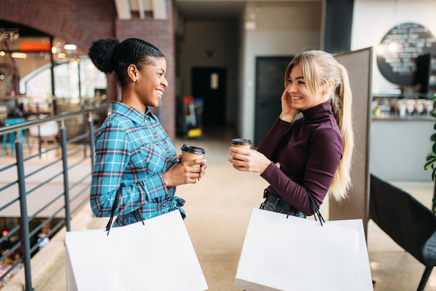 White and black females with shopping bags in mall