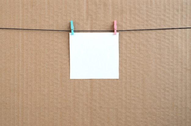 White blank card on rope on a brown cardboard background. 