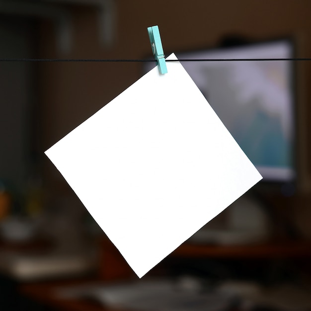 White blank card on rope, dark office background. Creative reminder, small sheet of paper on wooden clothespin, memo