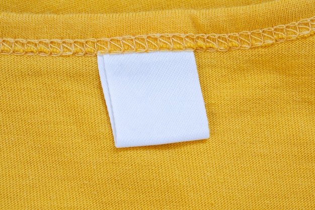 Photo white blank clothing tag label on new yellow shirt background