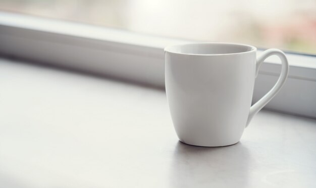 White blank Mug on windowsill at morning