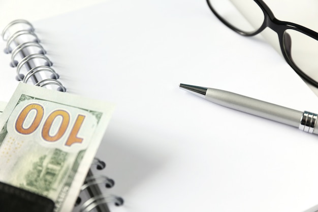 White blank notebook with silver pen and glasses and wallet with money