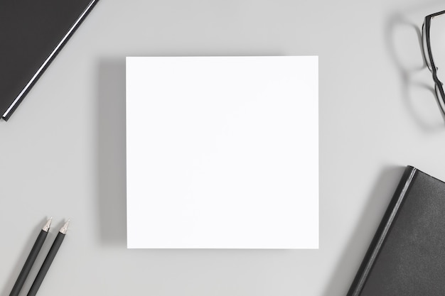 White blank square sheet of paper on office table Flat lay top view