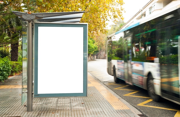 White blank vertical billboard at the bus stop on the city street