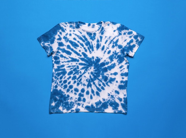 White and blue tie dye Tshirt on a blue background Flat lay