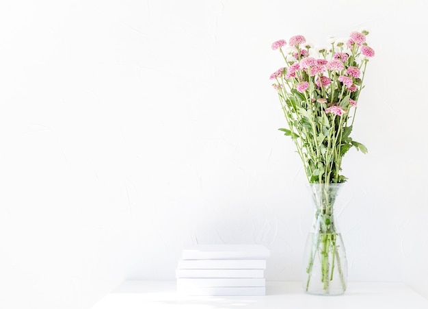 White book mockup with chrysanthemum flowers in a vase on a white table