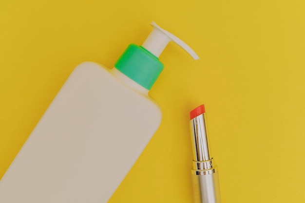 White bottle of makeup and lipstick on a yellow background