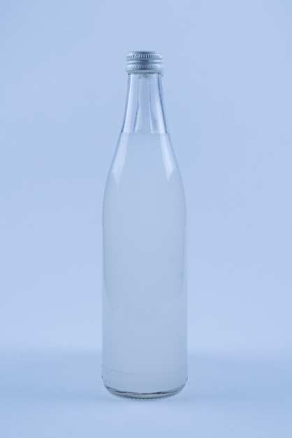 A white bottle with a soda drink on ice isolated on a white background.