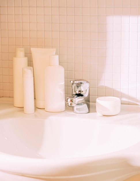 White bottles with various cosmetics stand on sink in bathroom Cleanliness and order in the house