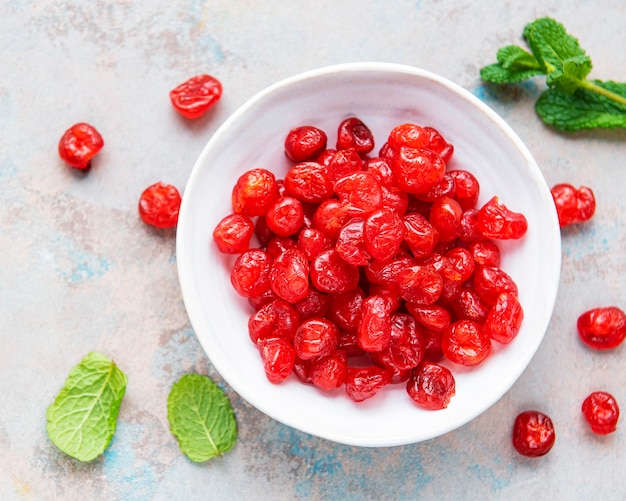 White bowl full of sweet dried cherries on concrete  background