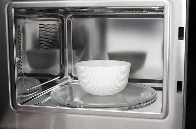 White bowl in modern stainless microwave oven