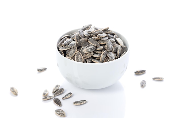 White bowl of sunflower seeds isolated on white background