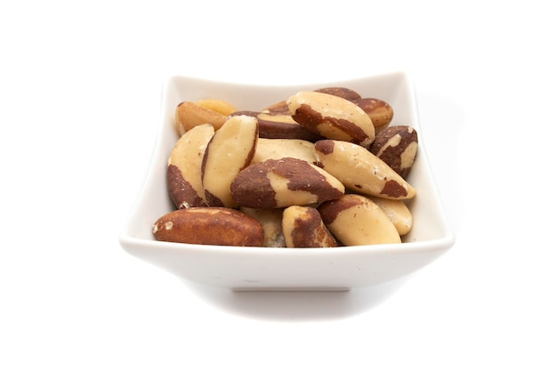 A white bowl with brazil nut or amazon nut isolated on white background Bertholletia excelsa