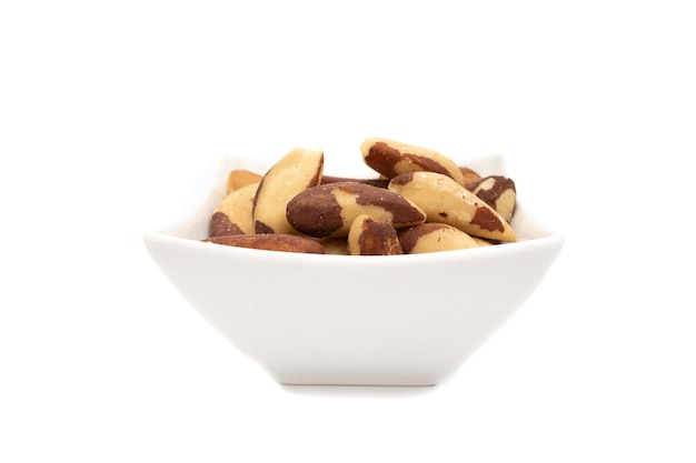 A white bowl with brazil nut or amazon nut isolated on white background Bertholletia excelsa