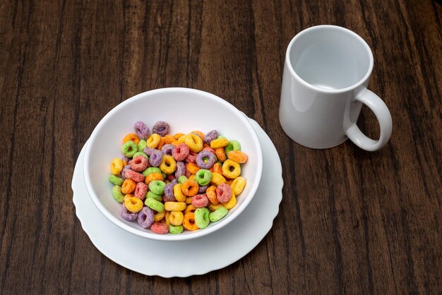 White bowl with cereal in the form of colored rings on wooden table Cereal breakfast