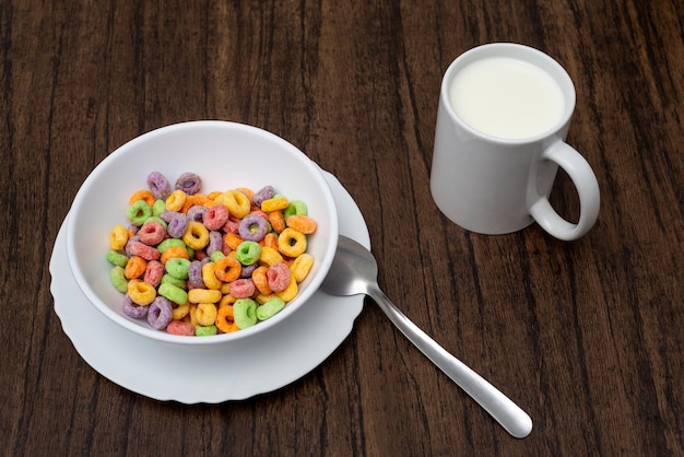 White bowl with cereal in the form of colored rings on wooden table Cereal breakfast