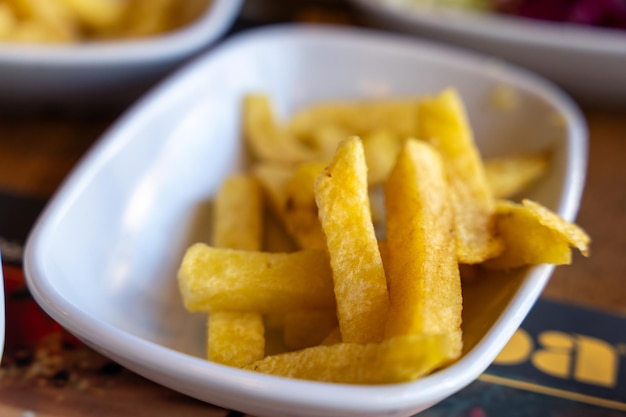 A white bowl with a pile of french fries in it