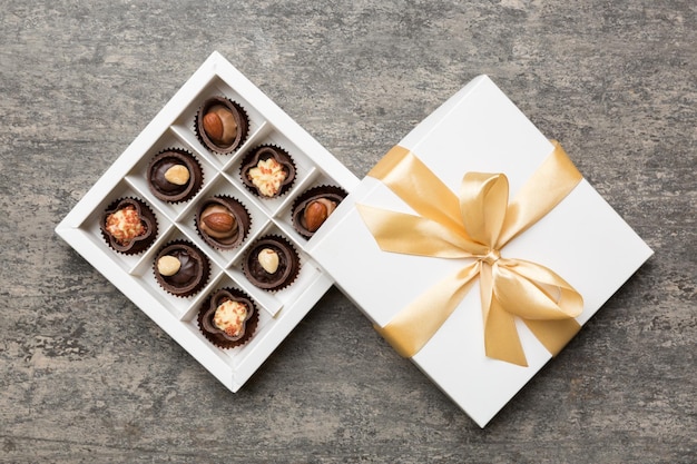 White box with chocolates candies and golden tape top view with copy space