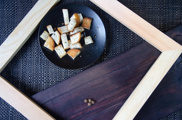 White bread croutons with spices on a black plate View from above