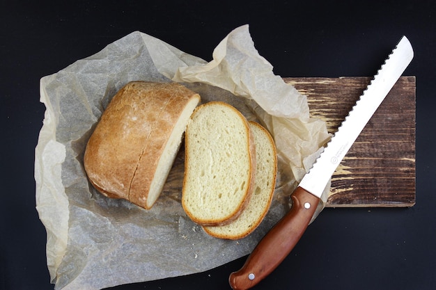 White bread and knife on wooden cutting board Crusty bread and old bread knife on chopping board