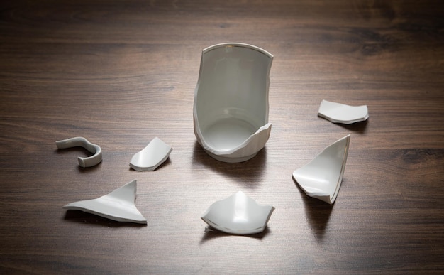 White broken cup on the wooden background