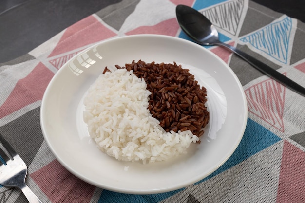 White and brown cooked rice arranged in circles on a white plate.