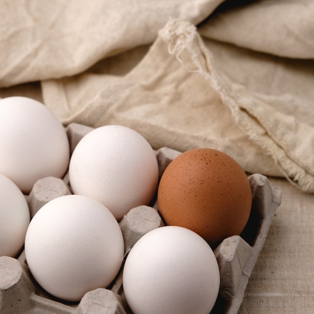 White and brown eggs lie side by side in a paper tray on the table