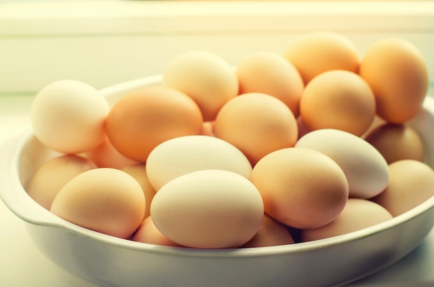 White and brown fresh chicken eggs in a plate. concept of easter. cooking ingredients