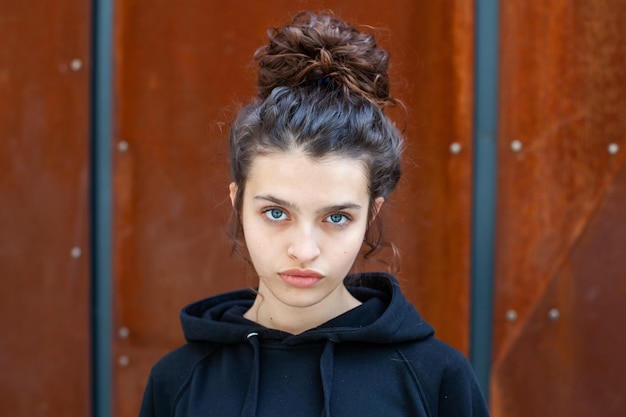 White brunette teenage girl with curly hair poses on the street in the city