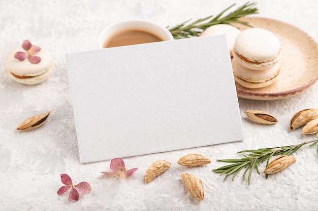 White business card mockup with cup of coffee almonds and macaroons on gray concrete background side view